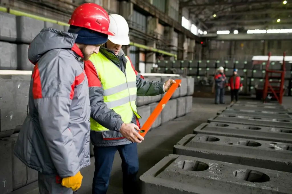 Factory workers inspecting quality of production at graphite plant.